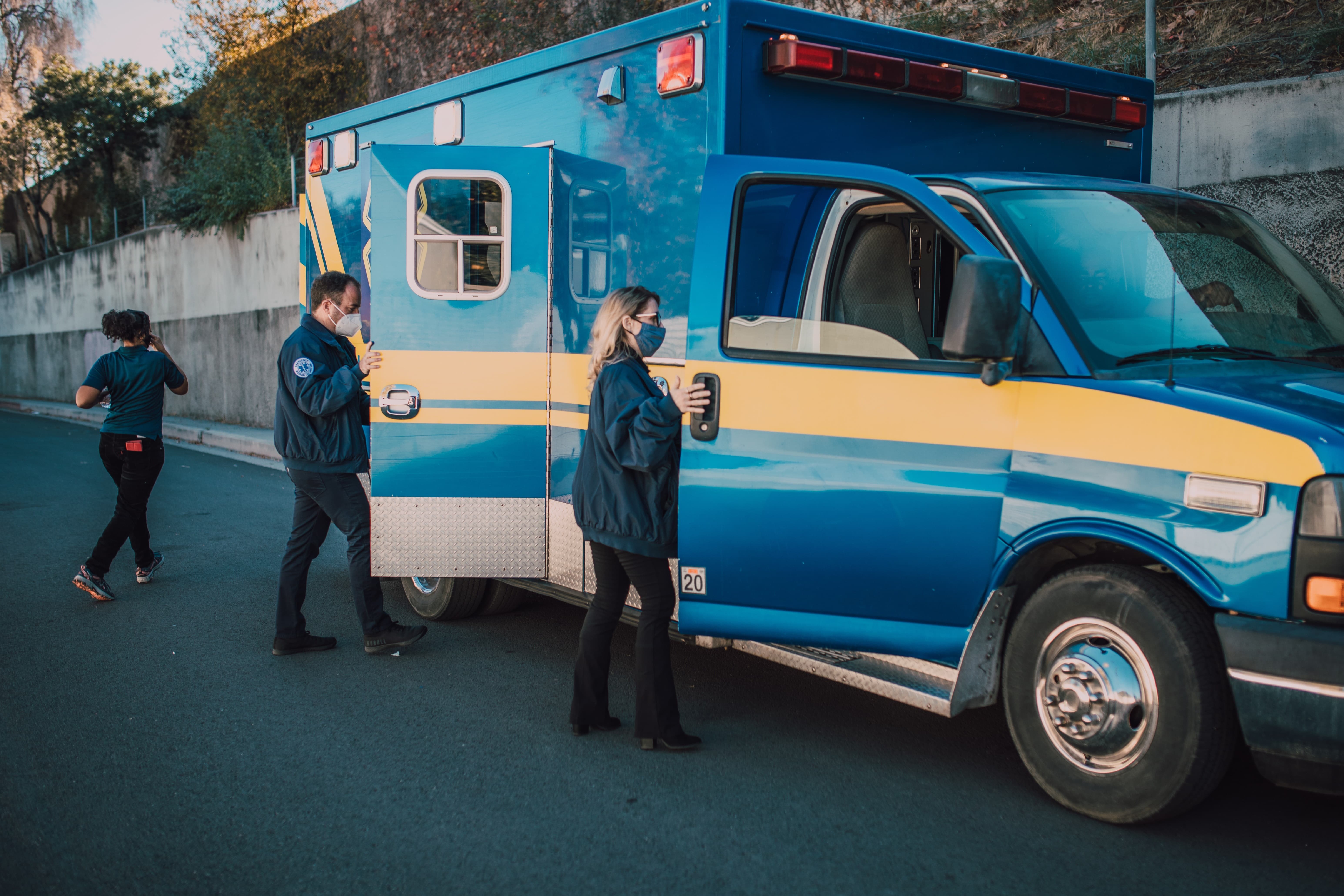 Masked paramedics boarding an ambulance