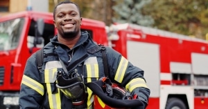 Smiling firefighter in front of a fire truck