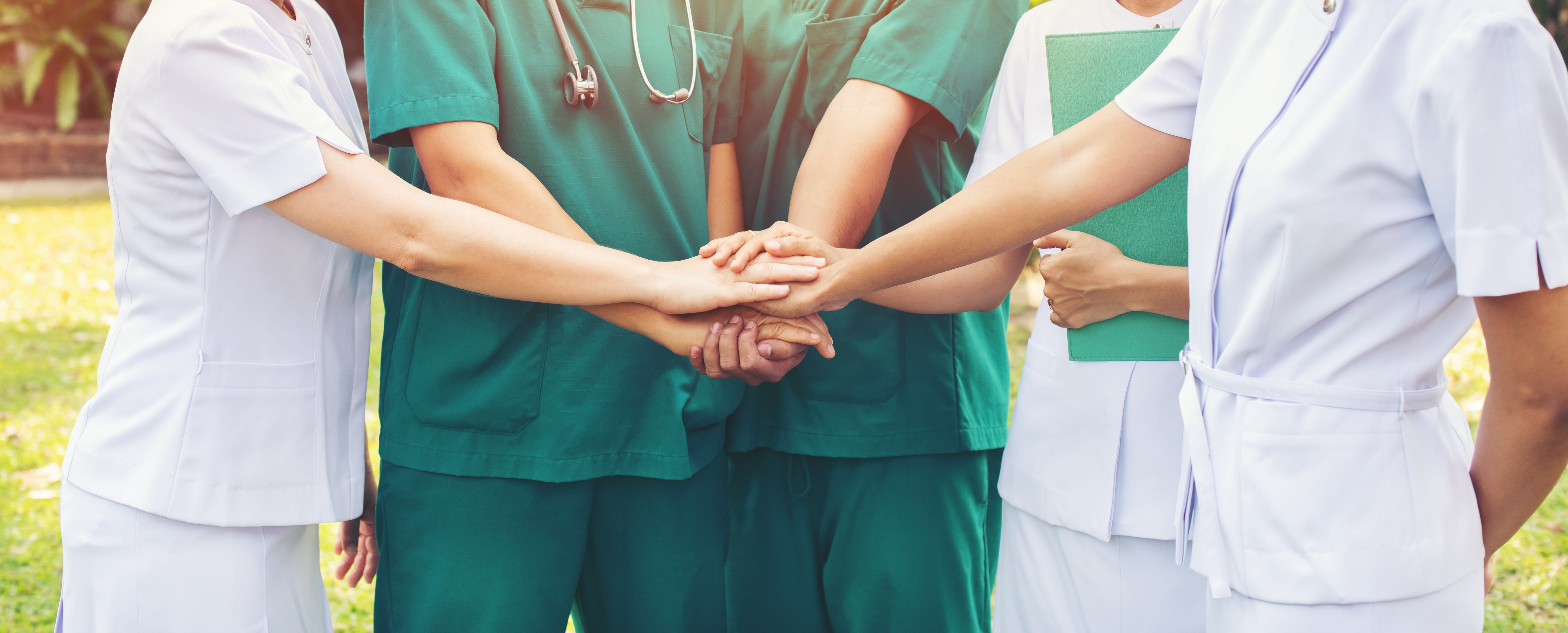 Healthcare team joining hands outside