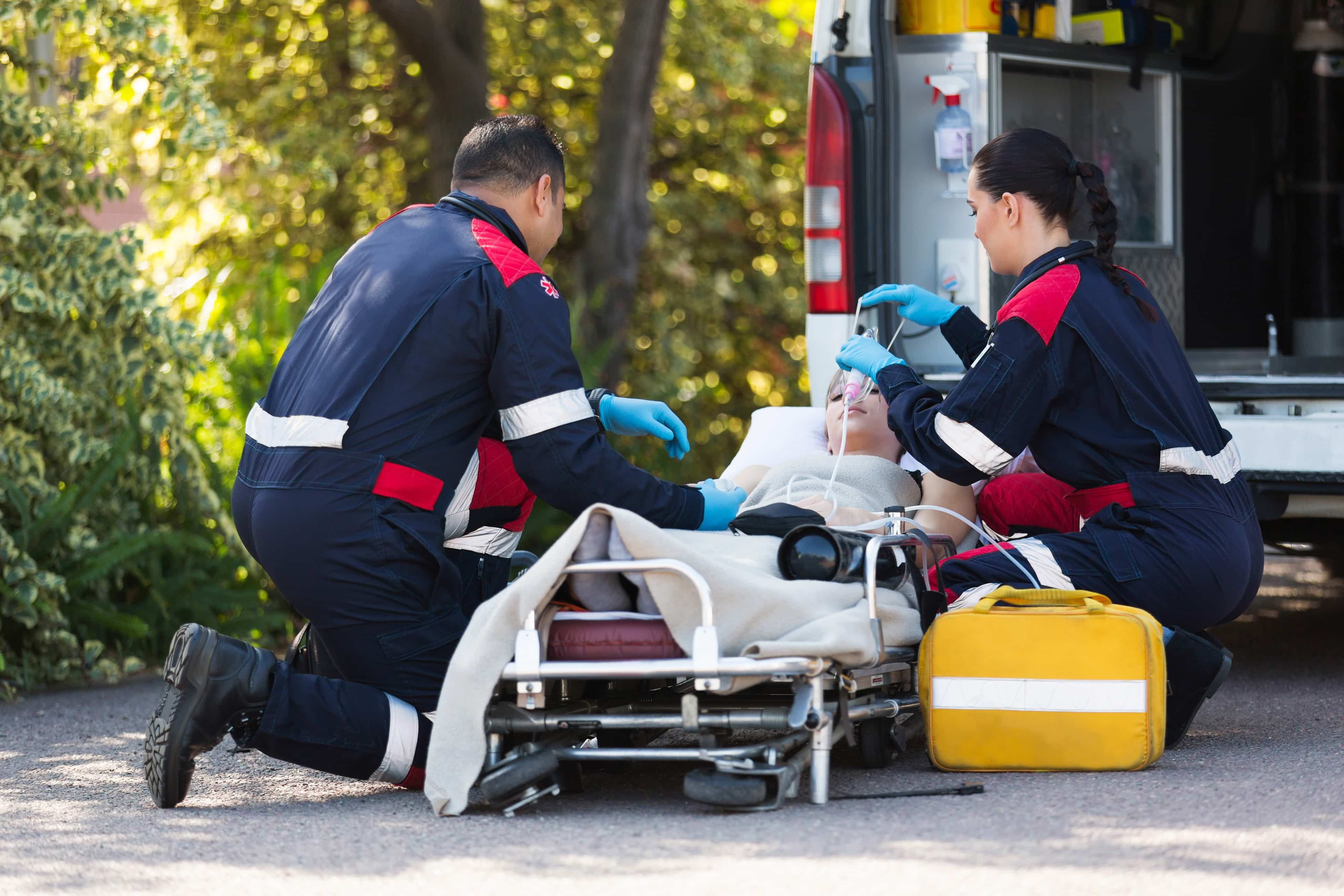 Two EMS professionals helping a woman on a stretcher