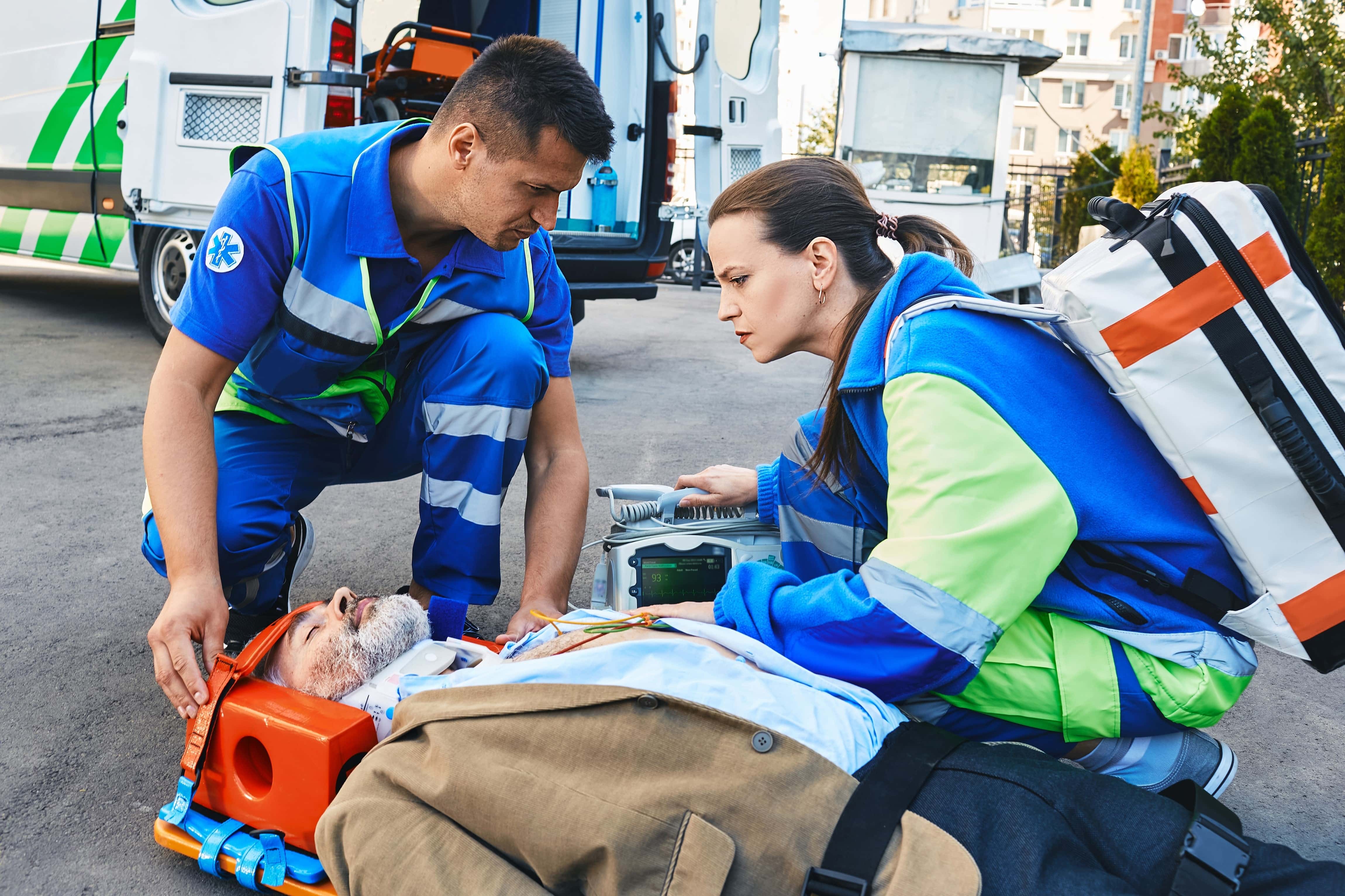 Two EMS professionals stabilizing a man on the road