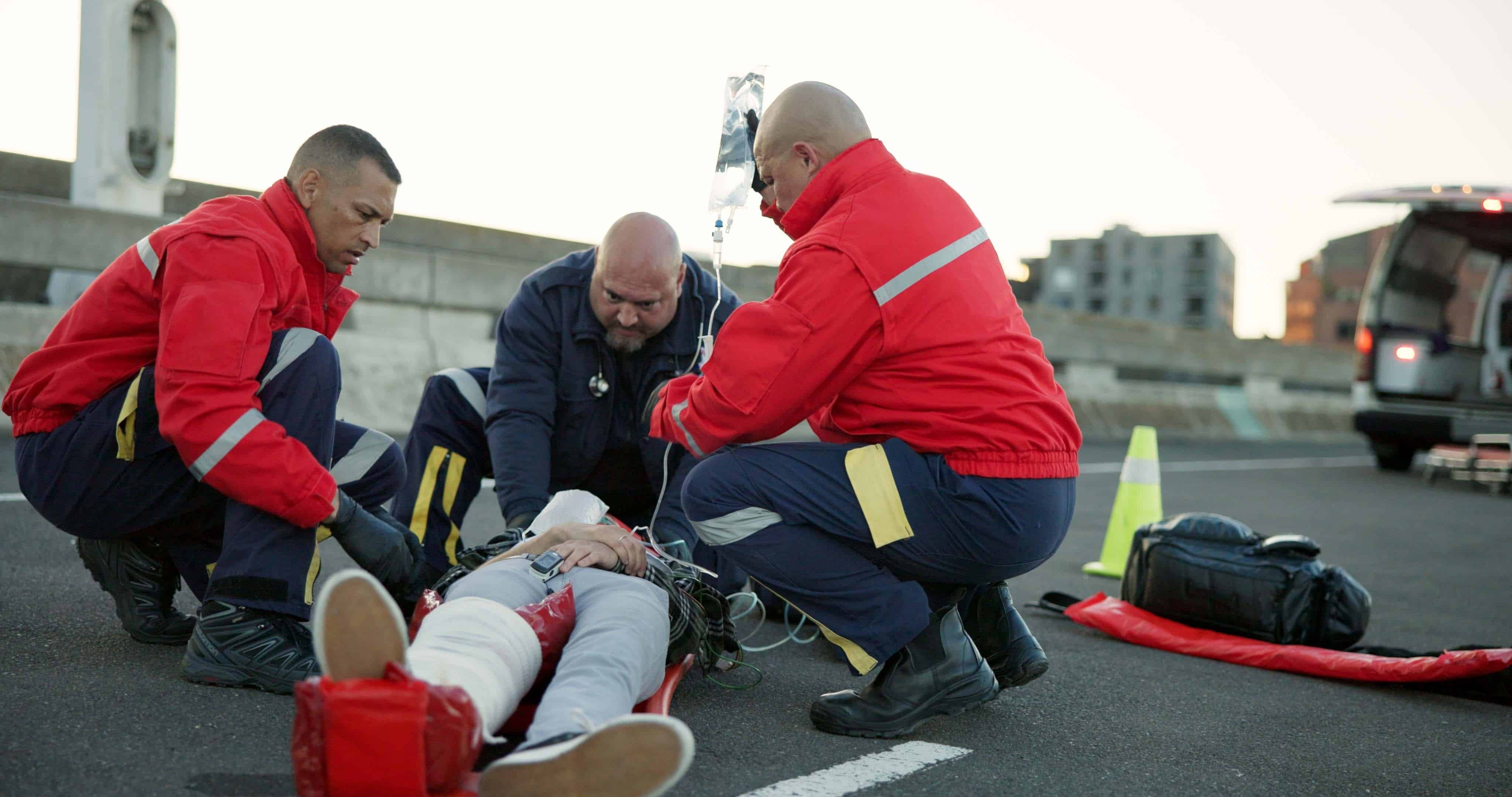 EMS professionals stabilizing a car crash victim on the road